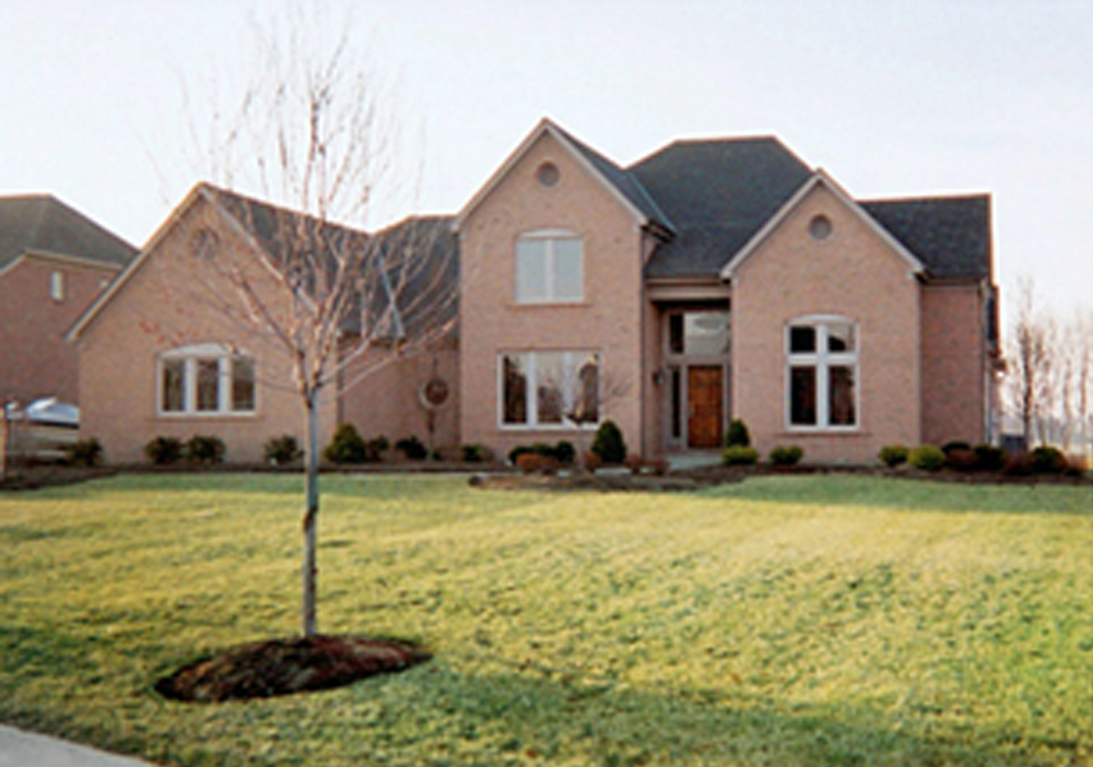 A large brick house with a tree in front of it