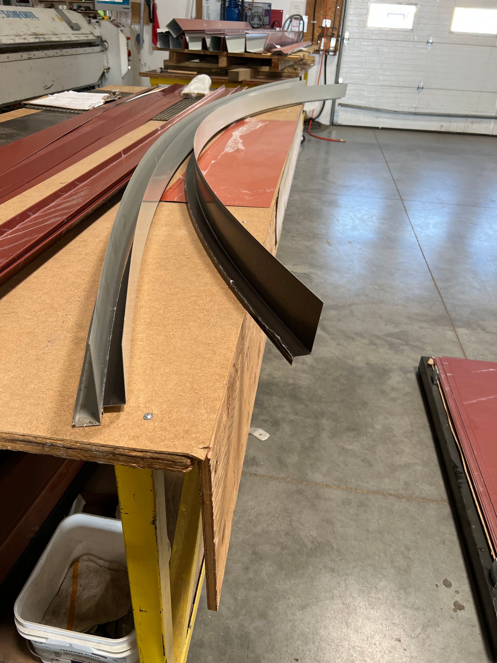 Curved black and red trim pieces on a workbench in a workshop