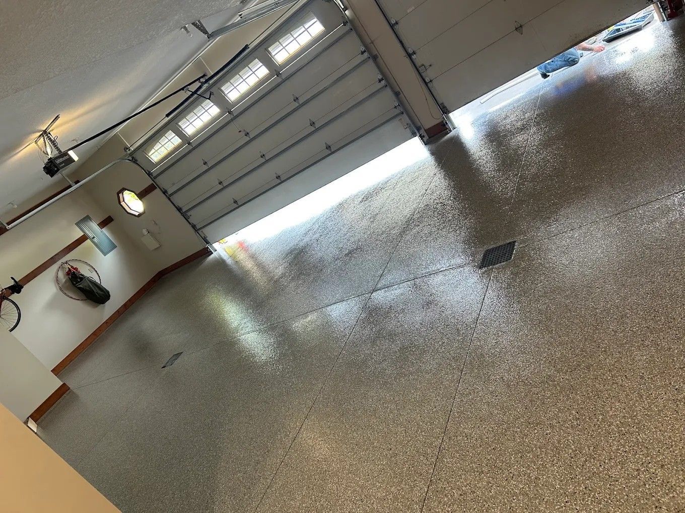 Empty garage with open door and wet concrete floor reflecting light.