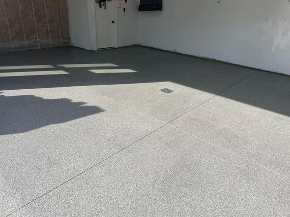 Empty tiled patio with shadows from a railing and bright sunlight on the floor.
