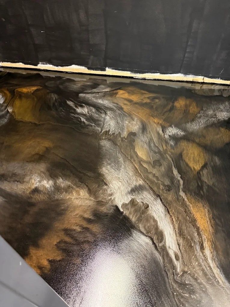 Close-up of a glossy black, gold, and white marbled floor under a dark wall.