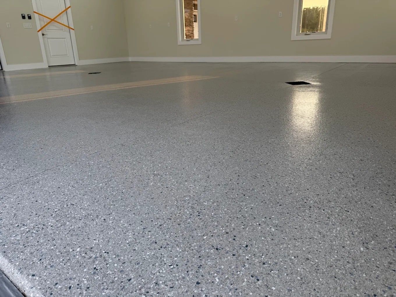 Empty room with gray speckled epoxy floor and beige walls, seen from low angle