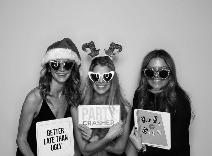 Three women are posing for a picture in a black and white photo booth.