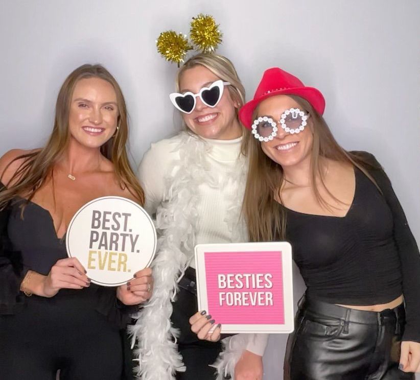Three women holding signs that say best party ever and besties forever