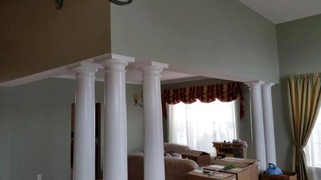 Interior with white columns, light green walls, window with curtains, and furniture.