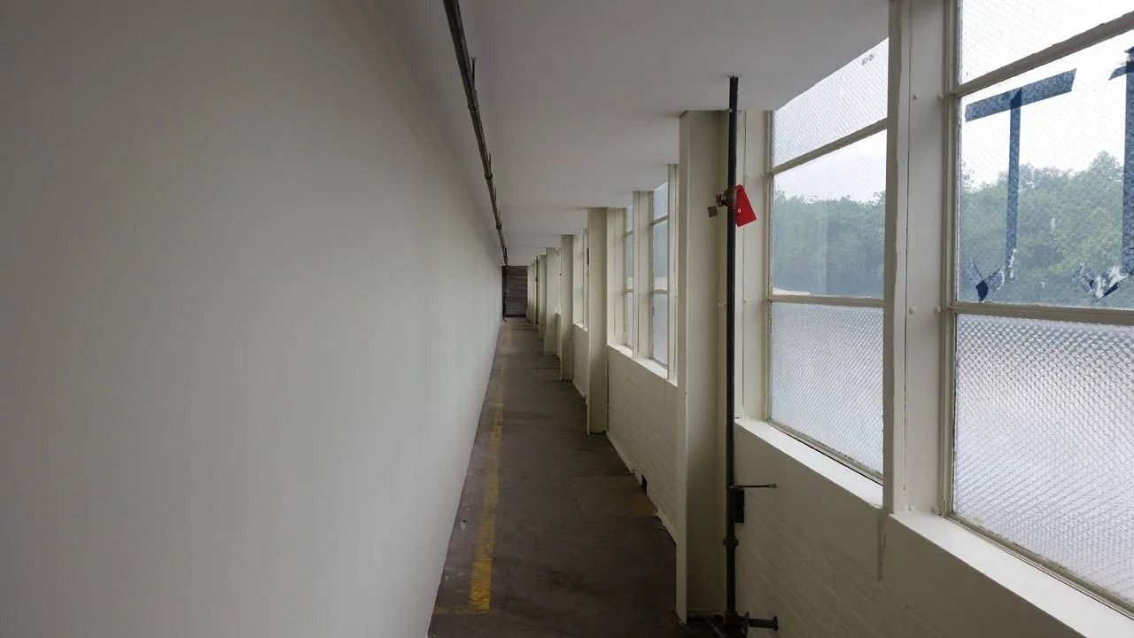 Long, narrow hallway with windows on one side and a plain wall on the other.