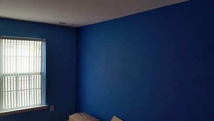 Blue-painted room corner with a window and white blinds. Two unidentifiable items are at the bottom.