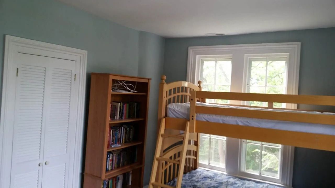 Bedroom with bunk bed, bookshelf, and white closet against teal walls.