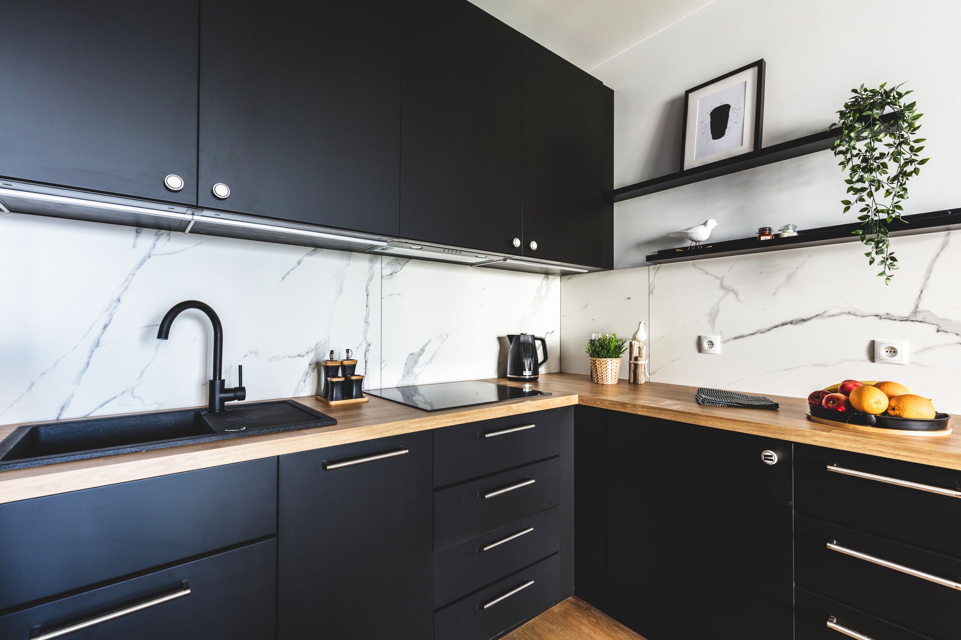 Modern black-and-wood kitchen with white backsplash, sink, stove, and countertop decor