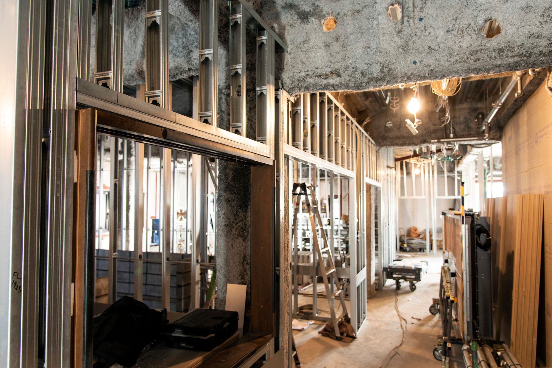 Unfinished interior with metal framing, exposed studs, and construction debris in a narrow hallway
