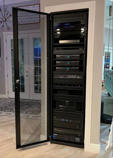Open home network equipment rack behind a glass door in a hallway