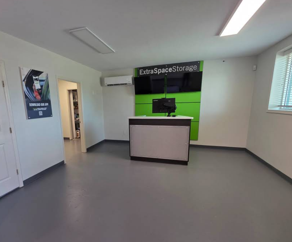 An Extra Space Storage office with a reception desk, a lime green accent wall, and a doorway to a back room.