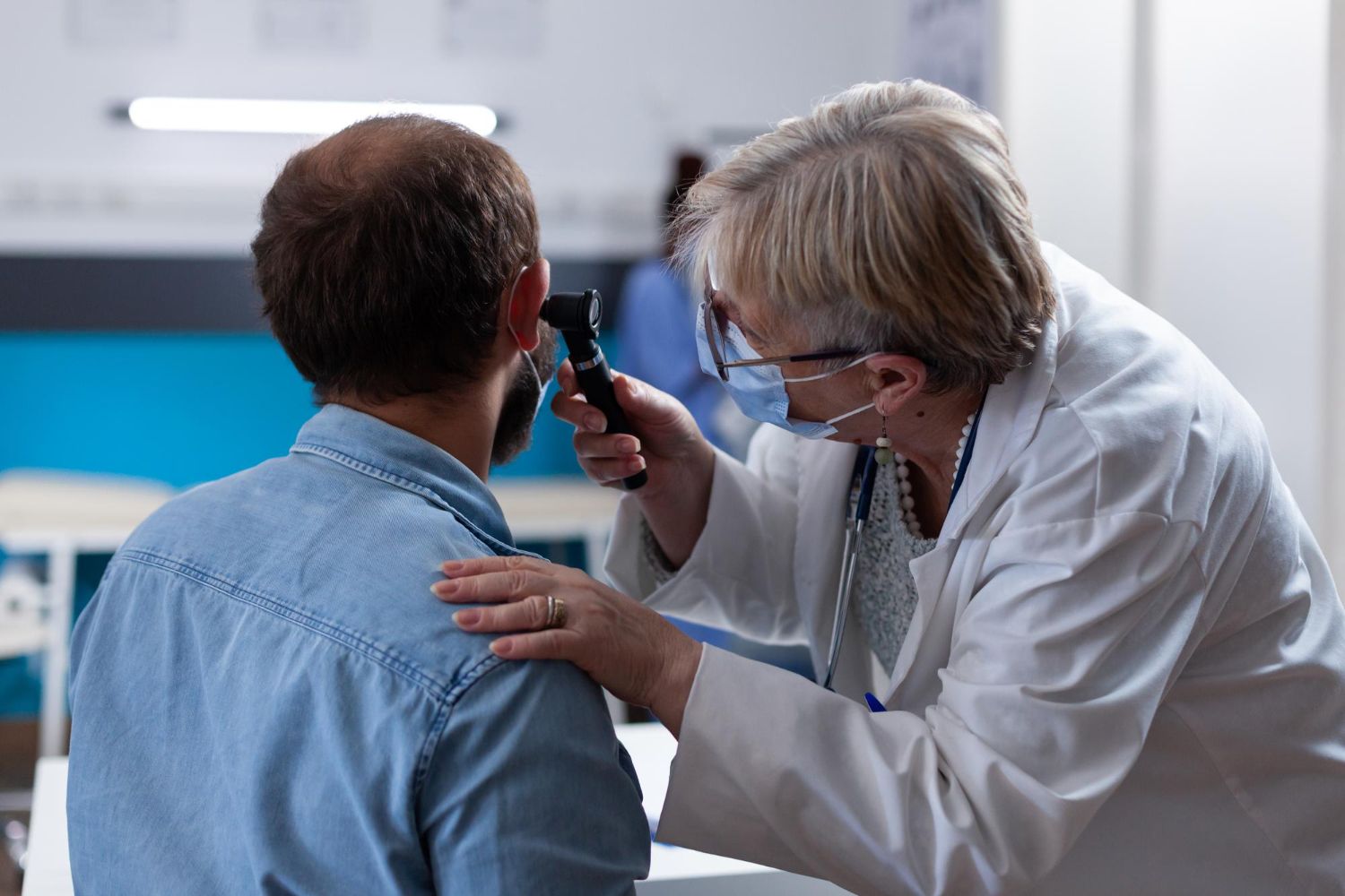 Doctor examining a patient’s ear with an otoscope in a clinic room