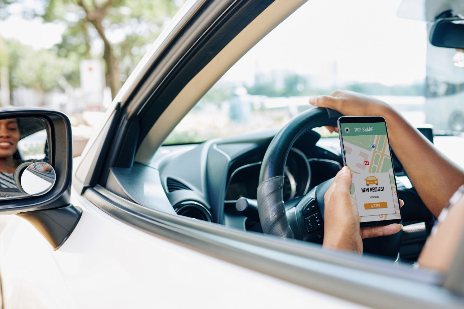 Driver holding a smartphone with a map app while sitting in a car
