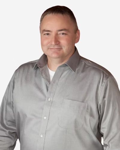 Smiling man in a light gray button-up shirt against a white background