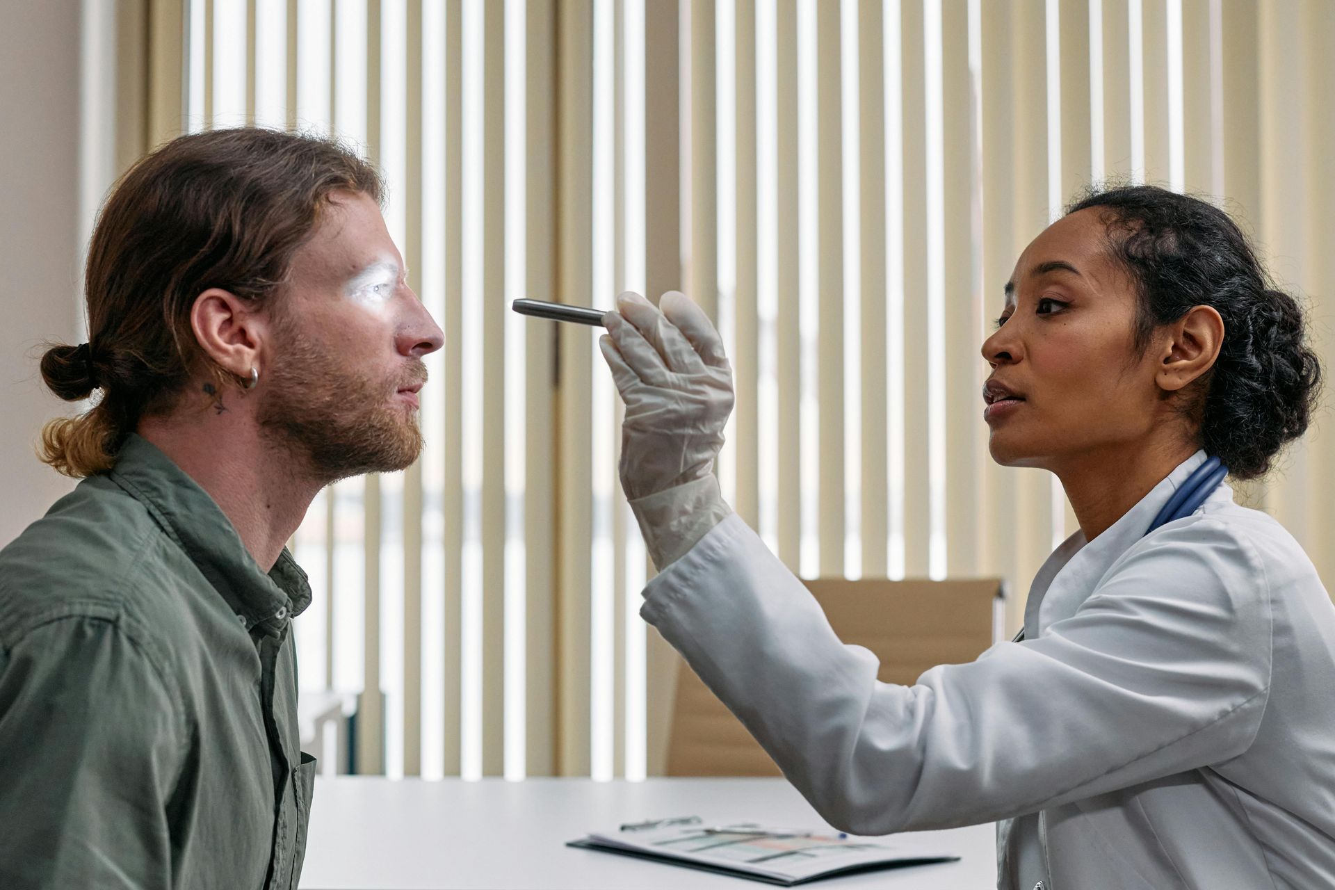 Doctor examining a patient's throat with a tongue depressor in a clinic