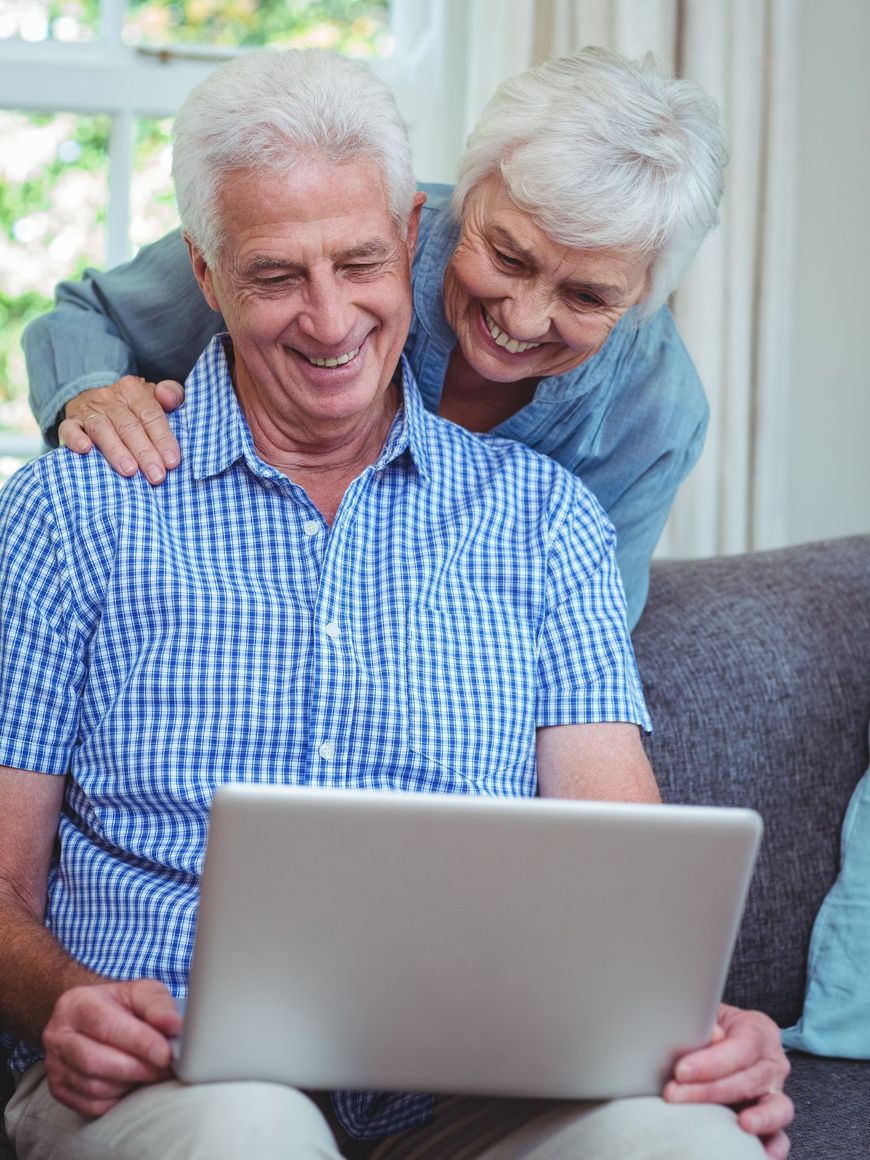 Smiling couple on a couch using a laptop together