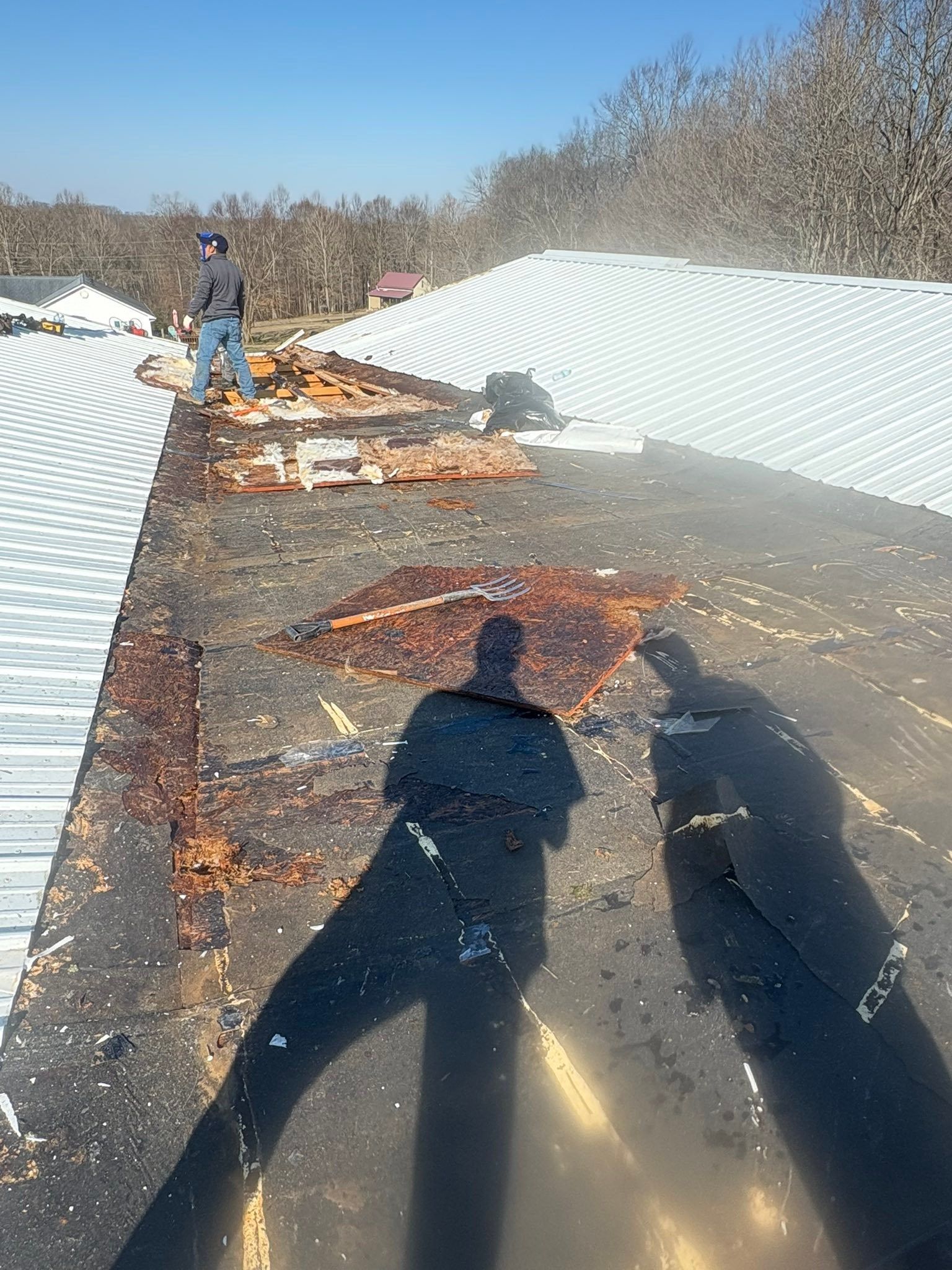 Roof workers repairing storm-damaged shingles on a snowy rooftop