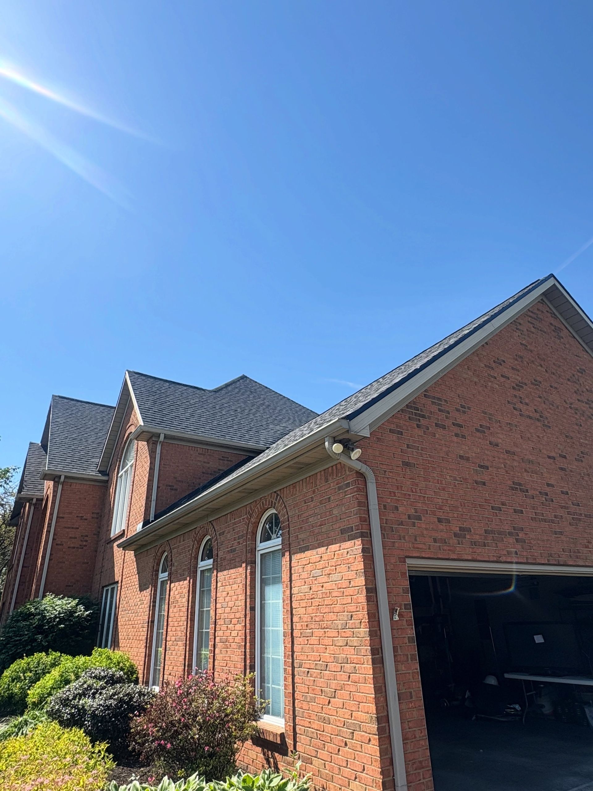 Red brick houses with tiled roofs and a garage under a bright blue sky