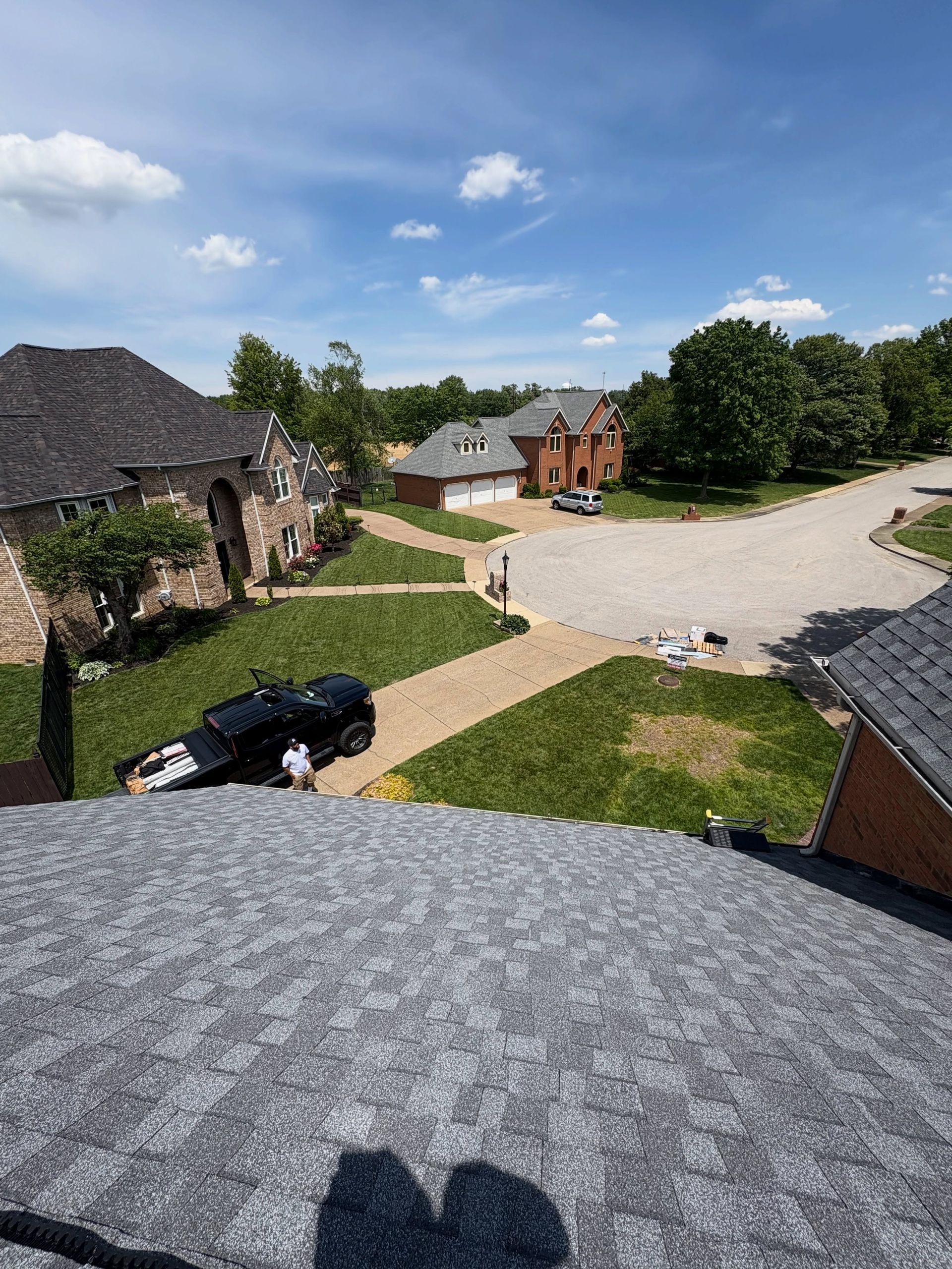 Aerial view of a rural courtyard with stone buildings, a parked black car, and a winding gravel road.