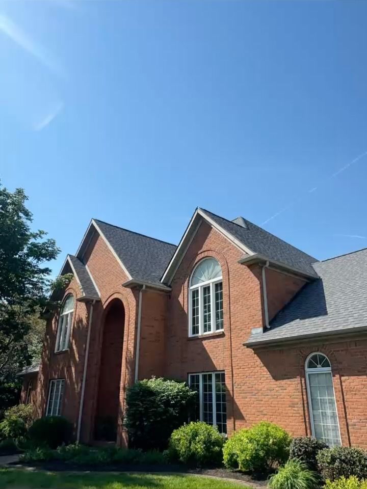 Brick suburban house with gabled roof and arched windows under a clear blue sky
