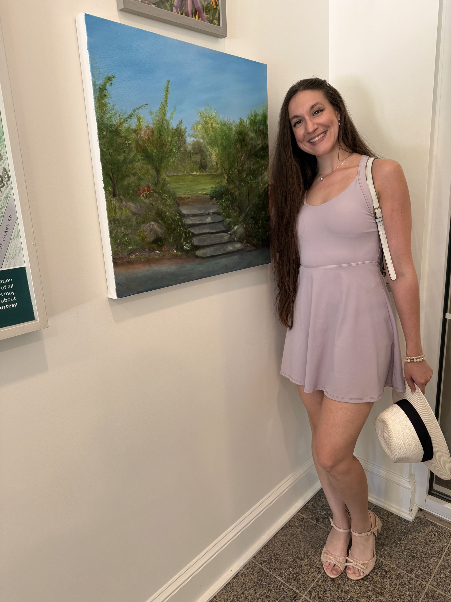 A woman is holding a painting on an easel.