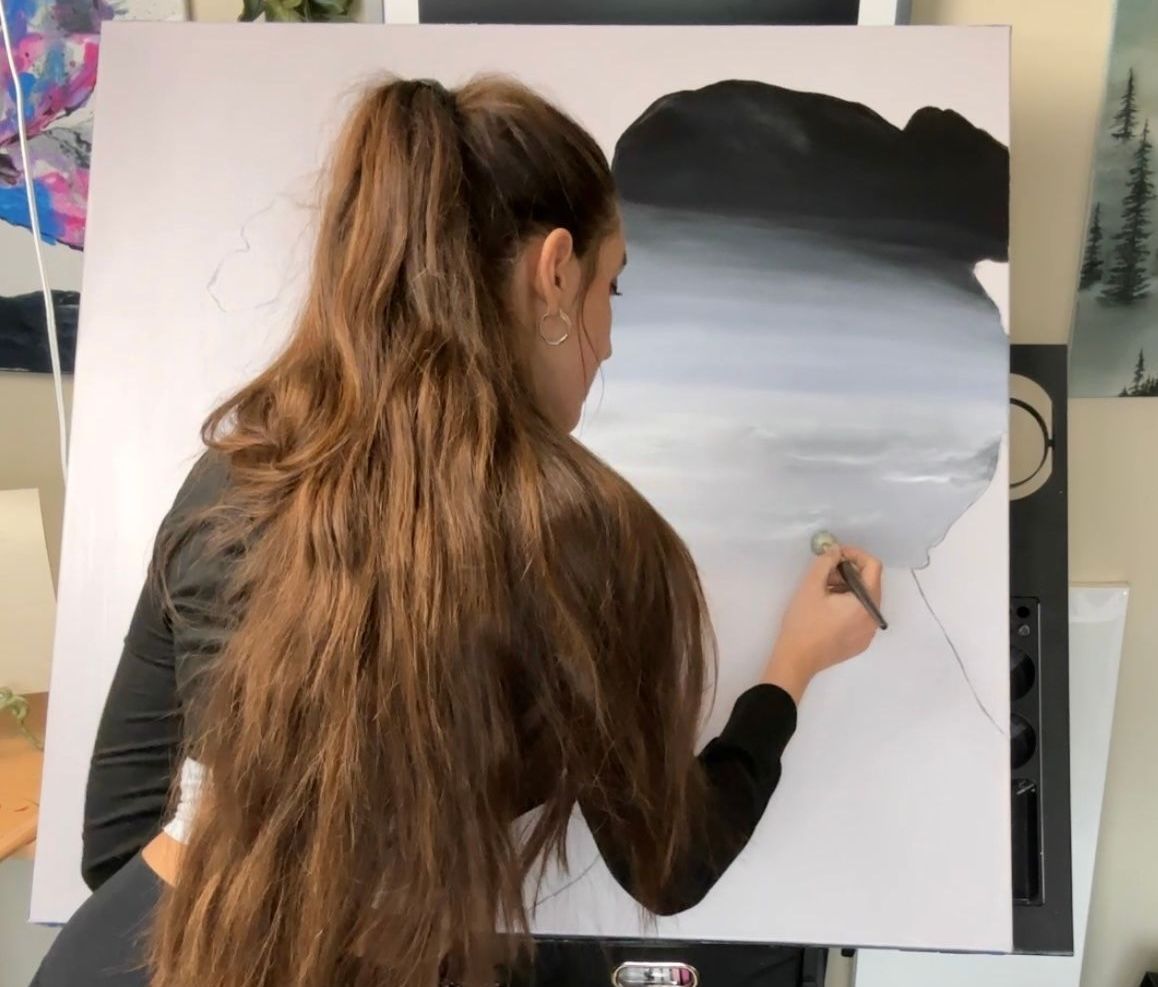 landscape and visionary artist Nicole Ann painting with a mop paintbrush 'she's got soul' on canvas, a depiction of what the soul looks like inside, showcasing a galaxy, clouds, and a plain light background