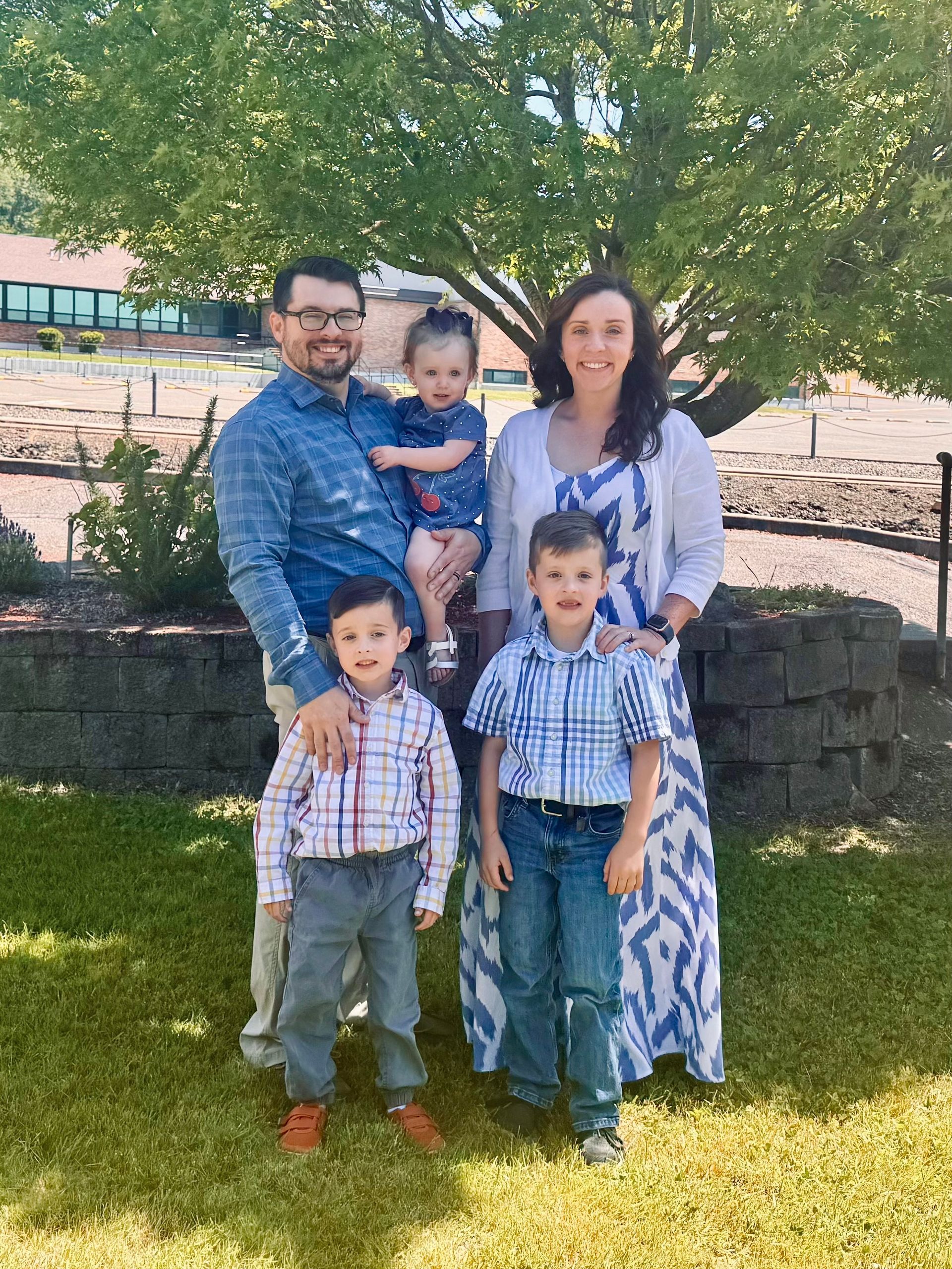 Family of five posing outdoors; man, woman, and three children.
