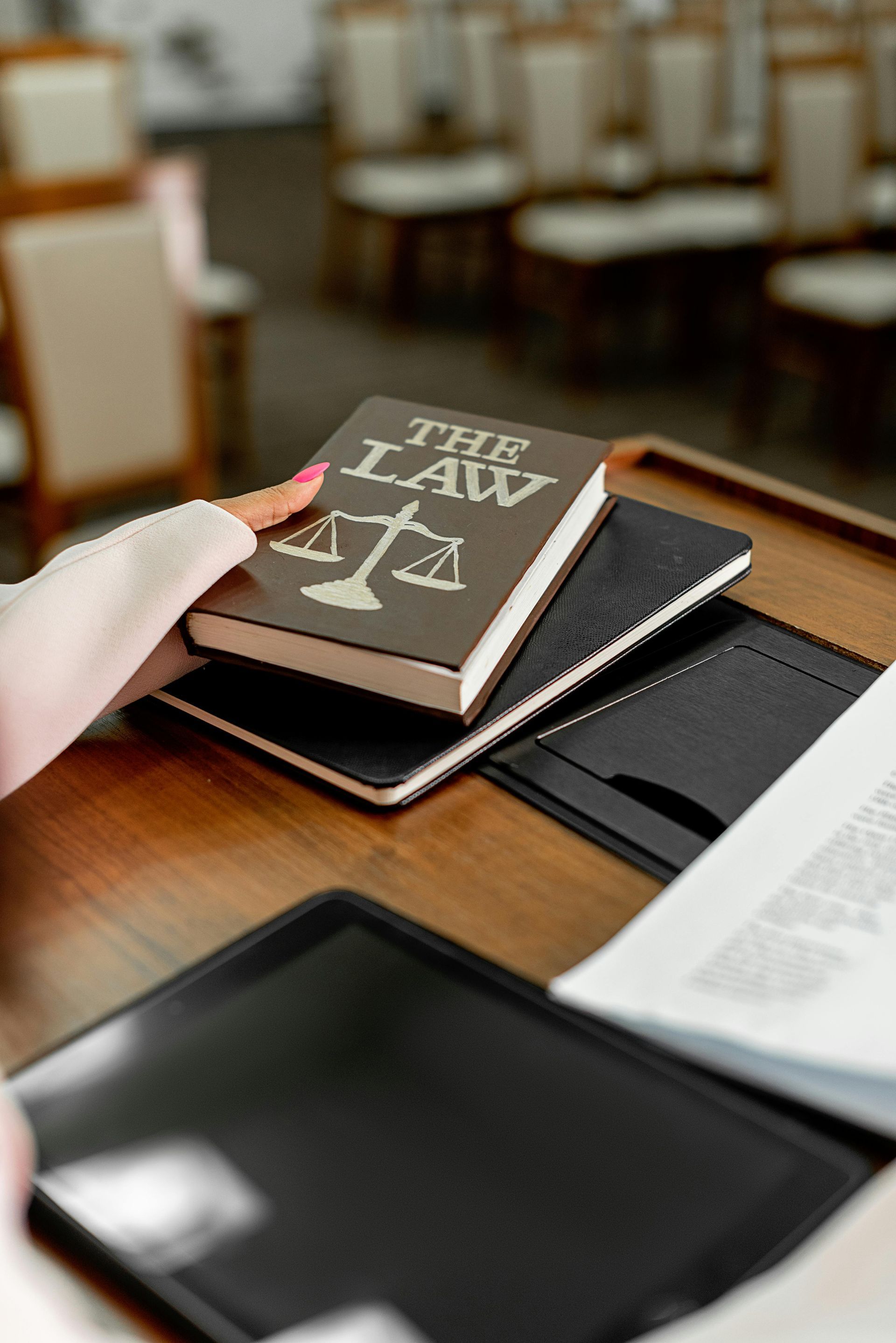 Hand placing a law book on a stack of legal books at a courtroom desk