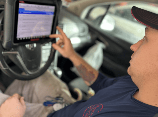 Person tapping a tablet mounted in a car interior while seated in the passenger seat | Quality Auto Center