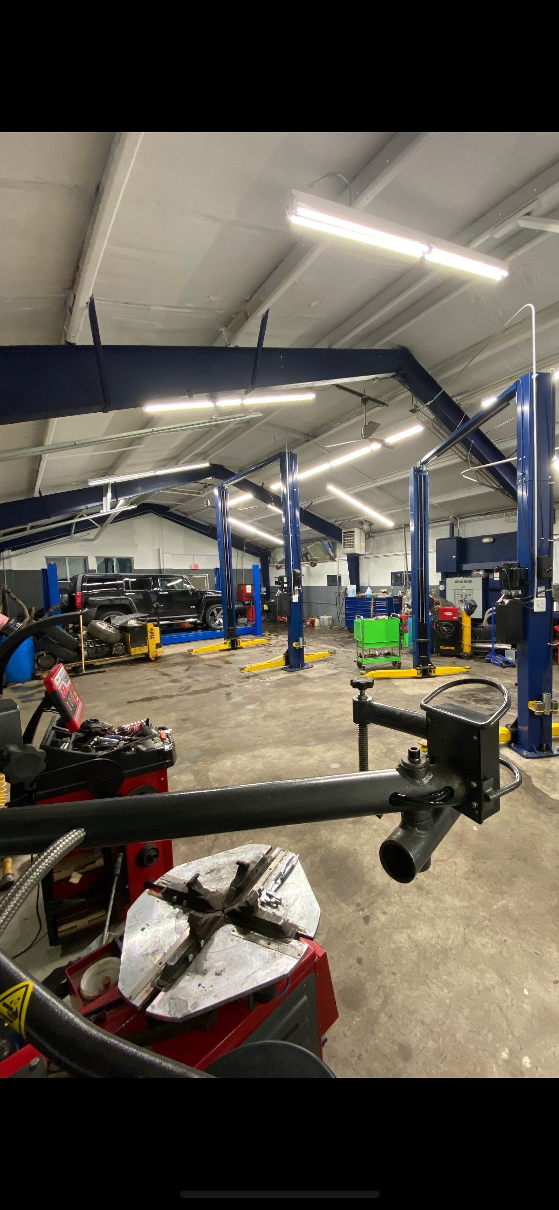 Auto repair shop interior with vehicles on lifts, tools, and a workbench under bright overhead lights | Quality Auto Center