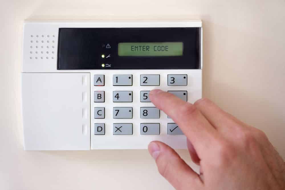 Hand Entering a Code on a White Security System Keypad — IRIS CCTV in Port Macquarie, NSW