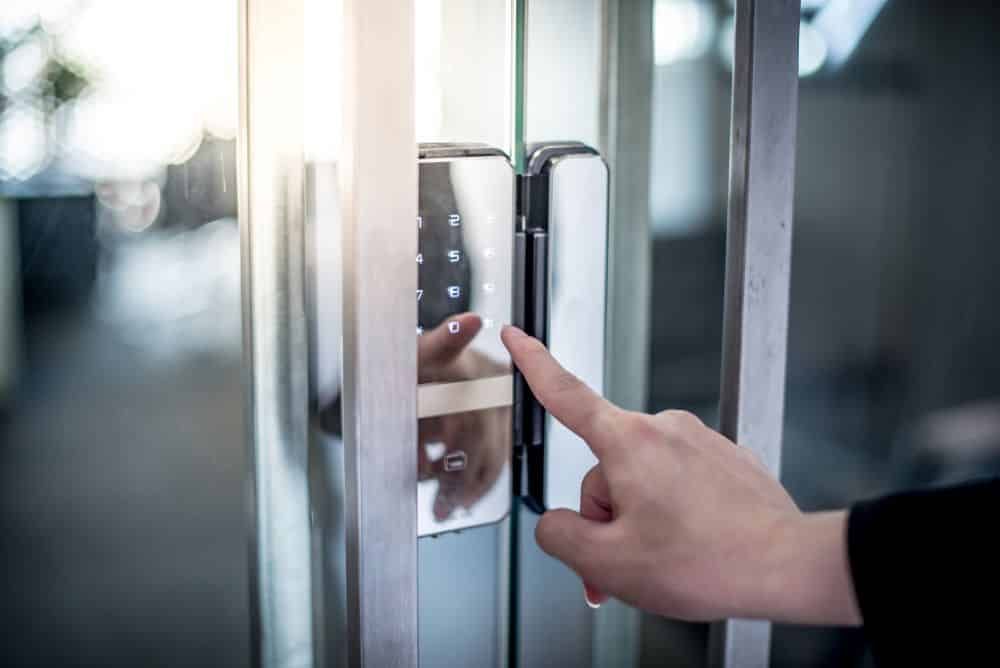 Person's Hand Entering a Code on a Digital Keypad Door Lock, Mounted on a Glass Door — IRIS CCTV in South Grafton, NSW