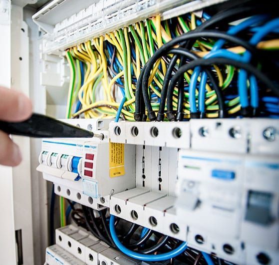 Electrician Working on Wiring Inside a Distribution Board With Colorful Wires — IRIS CCTV in South Grafton, NSW