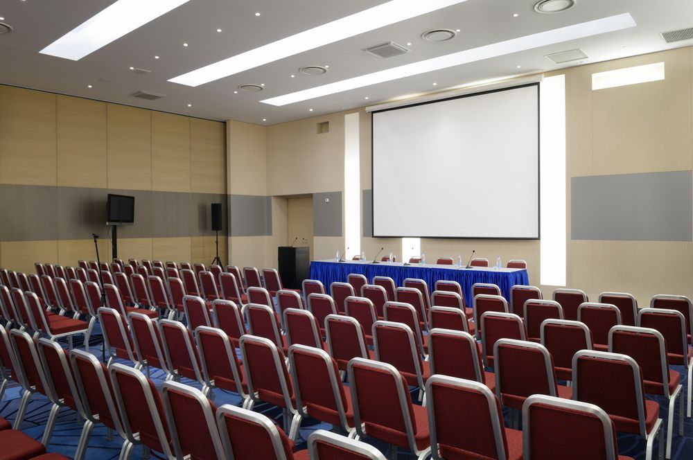 Rows of Red Chairs Face a Blue Table and a Blank Projection Screen in a Conference Room — IRIS CCTV in Grafton, NSW