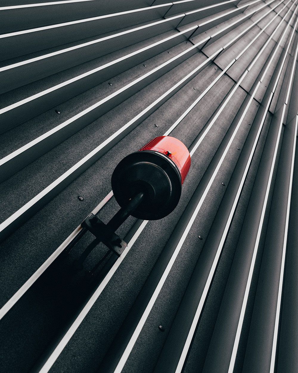Red and Black Light Fixture on a Dark Corrugated Metal Roof With White Stripes — IRIS CCTV in South Grafton, NSW