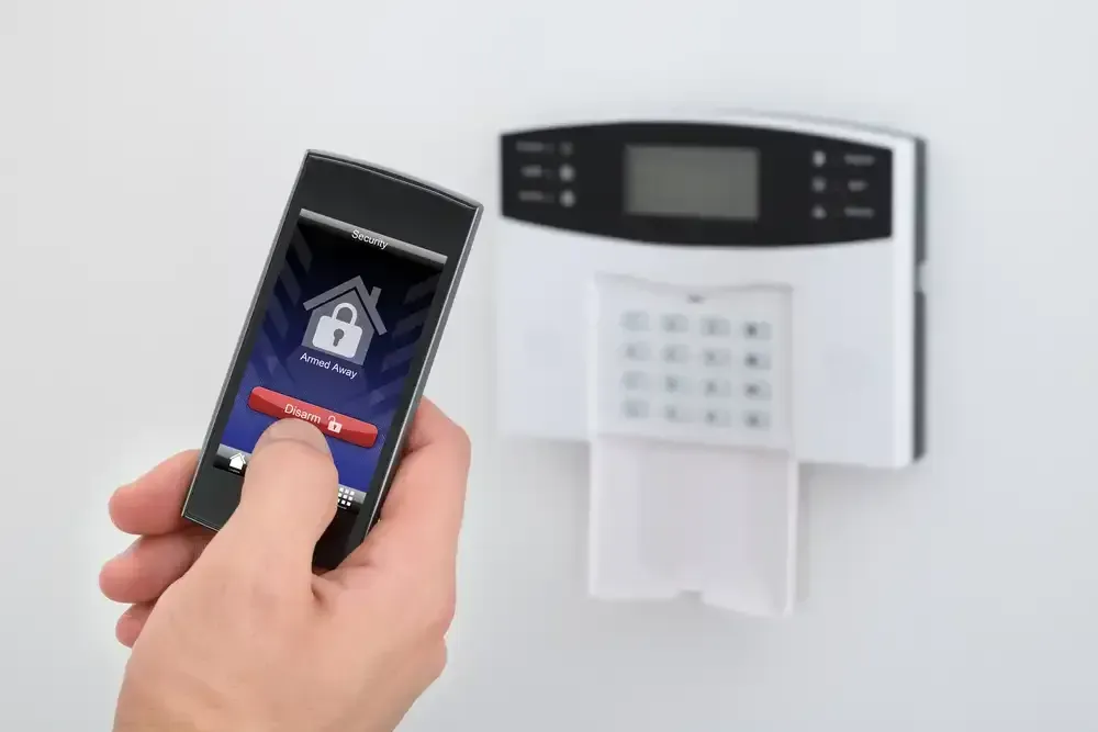 Hand Holding Phone Unlocking Home Security System Next to a Keypad — IRIS CCTV in South Grafton, NSW