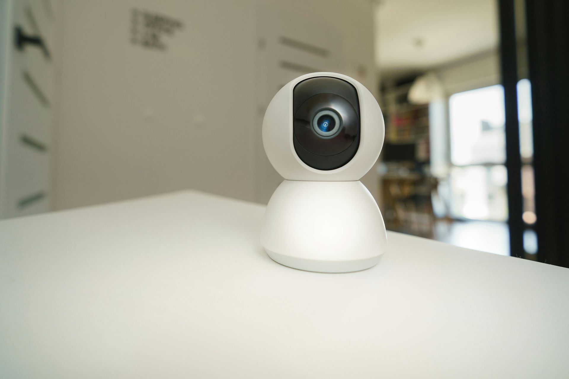 Security camera mounted on a wall, with a glowing blue ring, next to pipes.