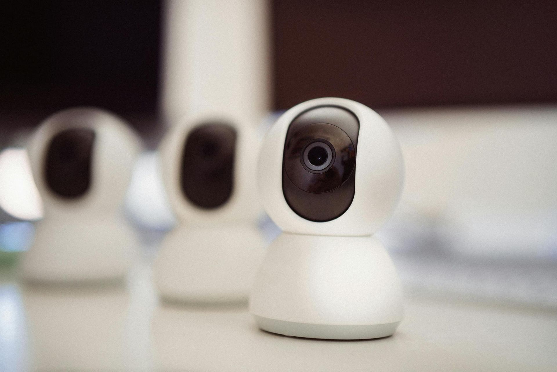 Three White, Dome-shaped Security Cameras on a White Surface, With One Camera in Focus — IRIS CCTV in Glen Innes, NSW