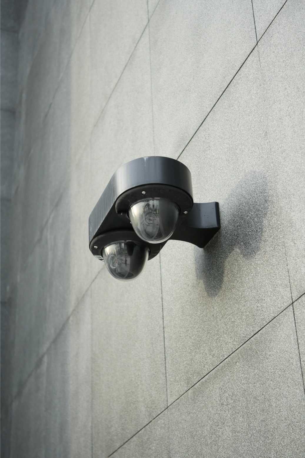Two Motion Sensors Mounted on a Textured Grey Building Wall — IRIS CCTV in Lismore, NSW