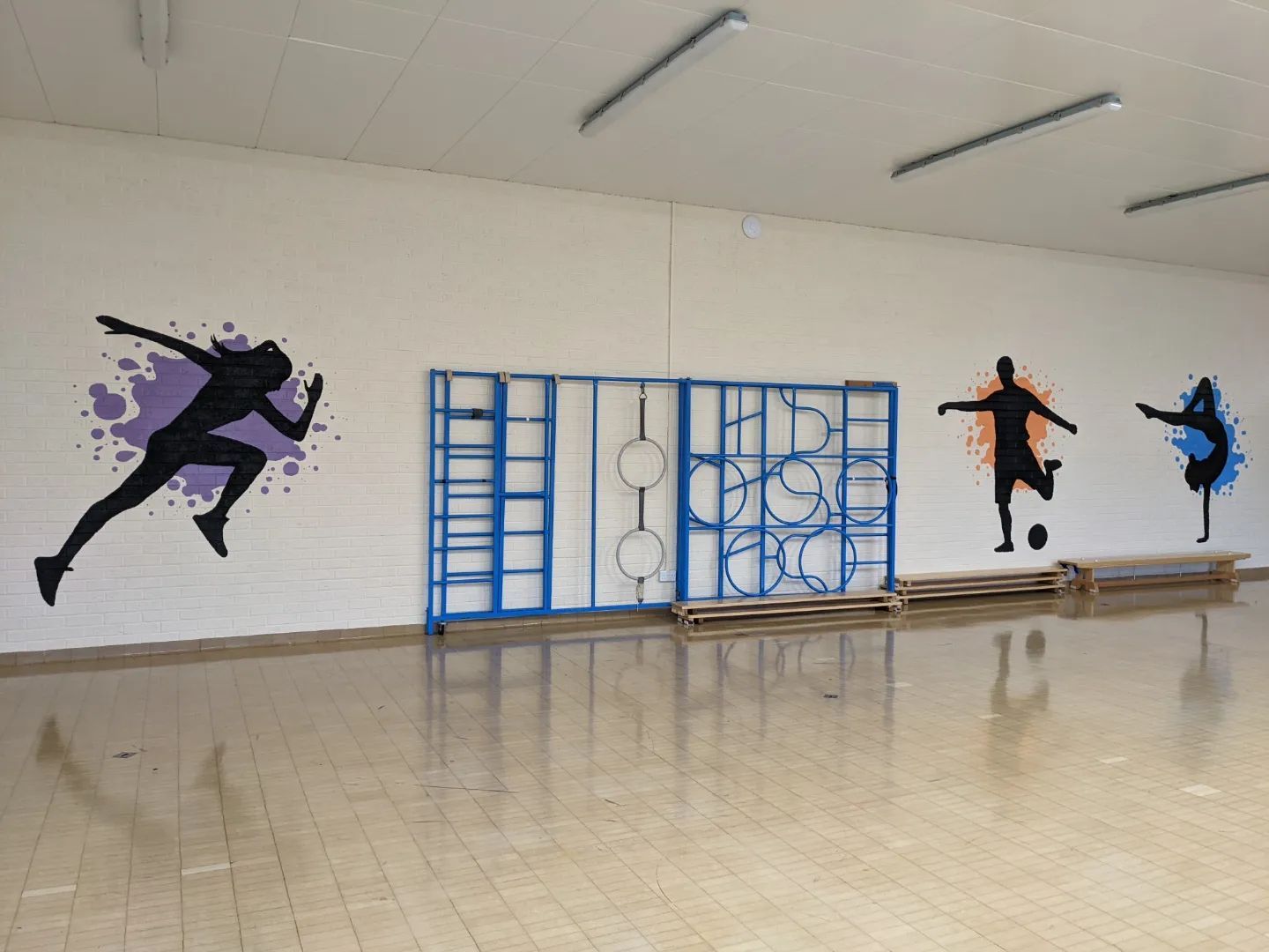 sports people silhouettes with a splash of colour behind them in a primary school hall hand painted murals  
