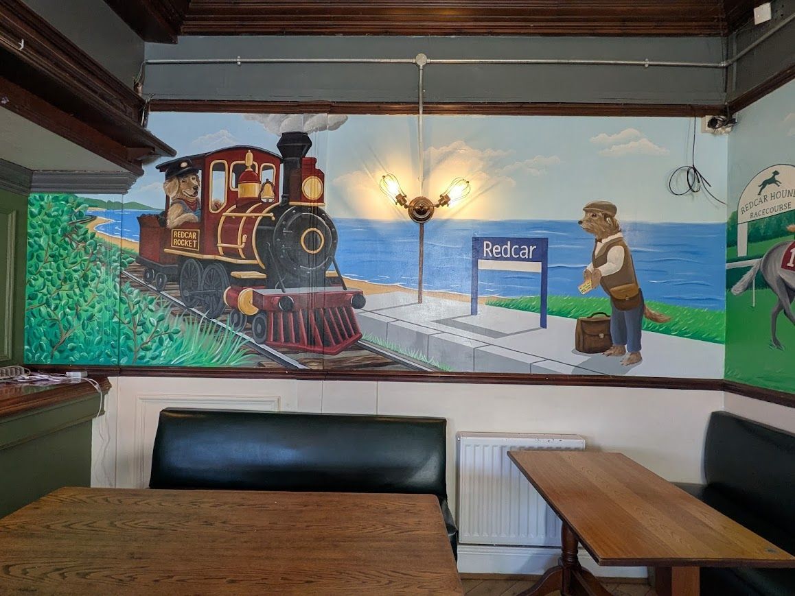 pub mural of a dog catching a train which is driven by a dog