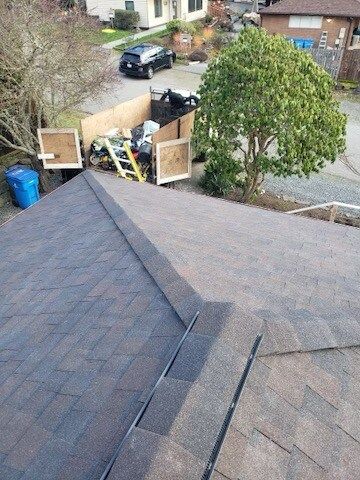 A roof with a ladder and a trash can on it.