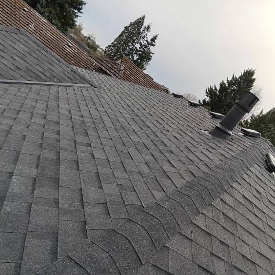 A roof with a lot of shingles on it and trees in the background.