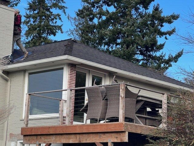 A man is standing on the roof of a house with a balcony.