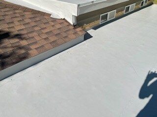 A white roof with a brown roof next to a house.
