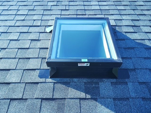 Blue skylight window on a shingled roof under daylight