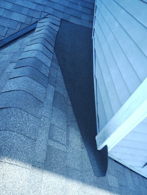 Roof shingles meeting white siding at a narrow corner seam