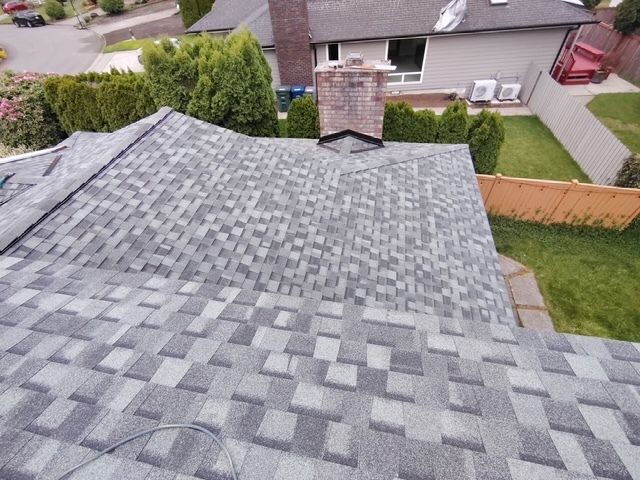 Gray shingled roof with chimney, viewed from above in a suburban neighborhood
