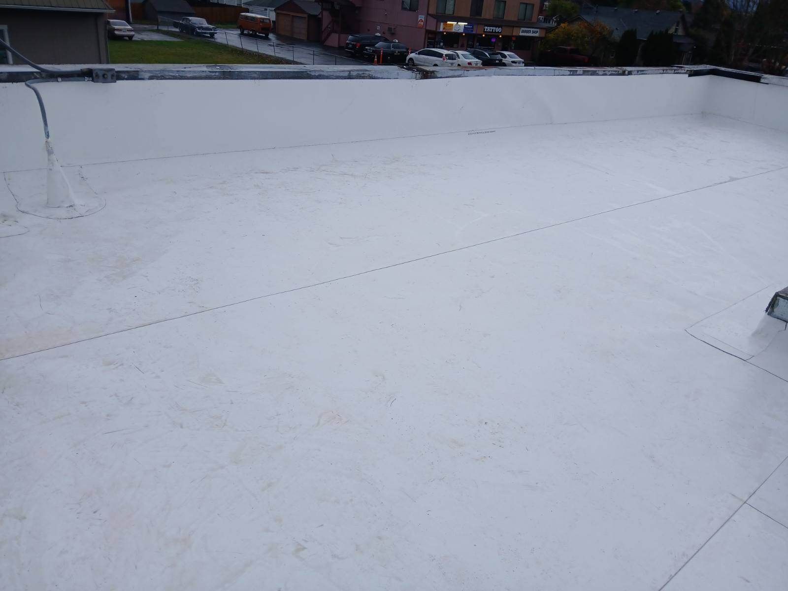 Snow-covered rooftop with a few footprints and distant buildings at the top edge